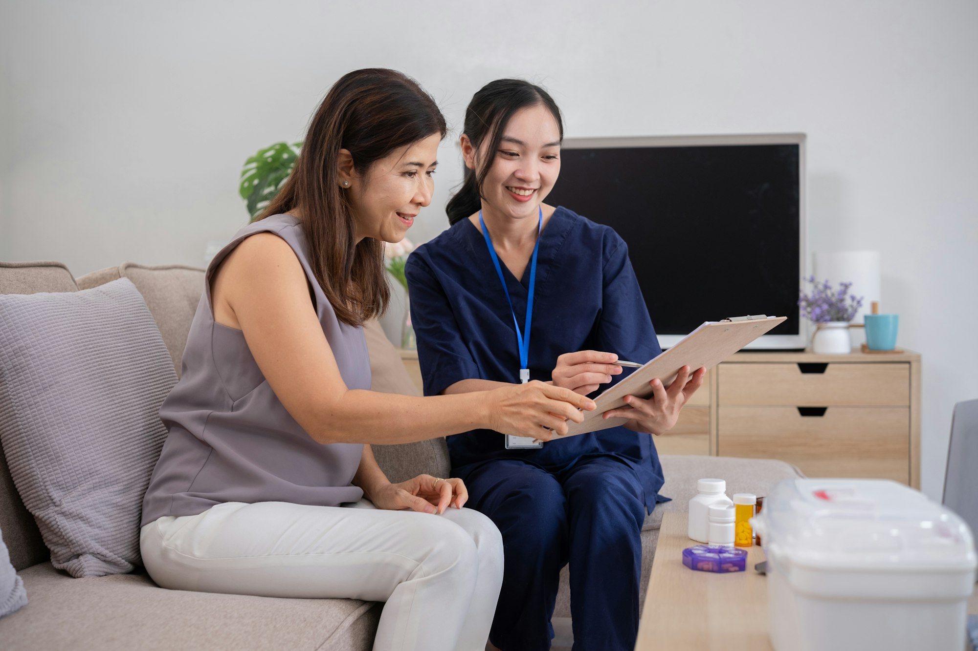 A caregiver is giving advice on health care and medication to an elderly woman at home.